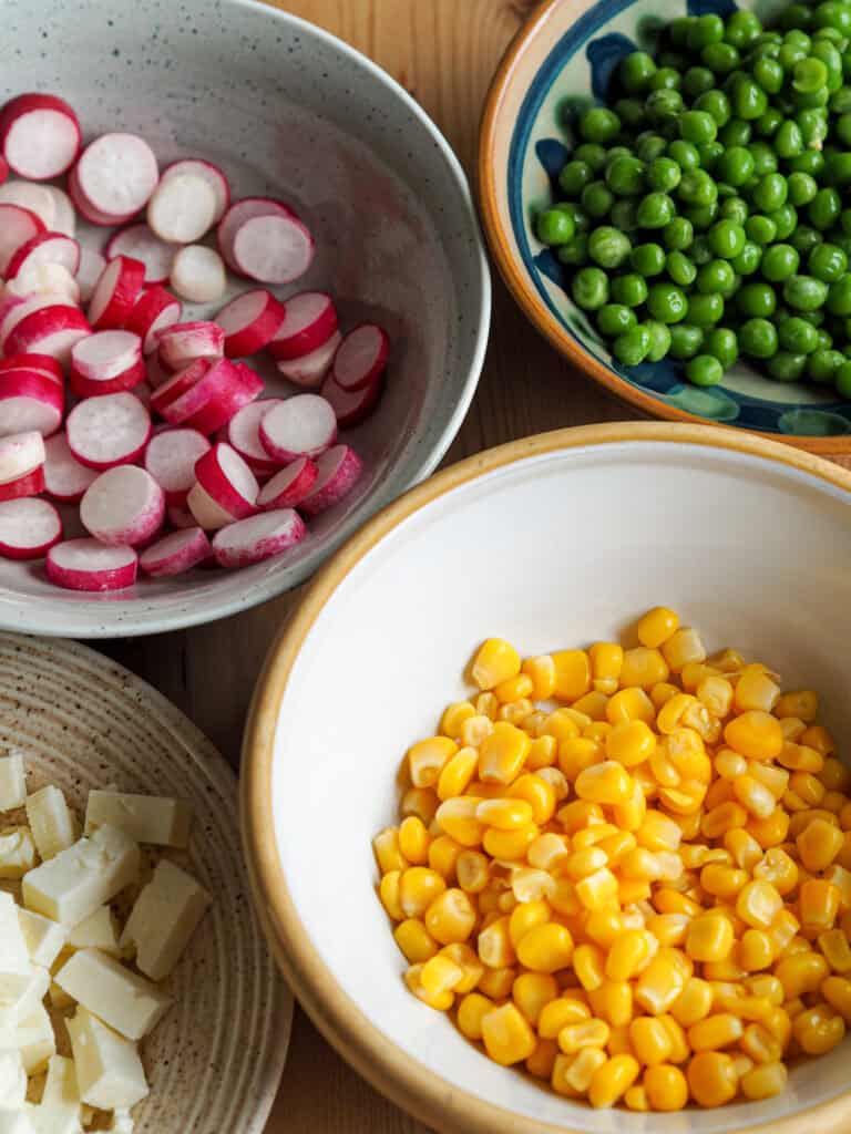 Små skåle med ingredienser til pastasalat med karrydressing