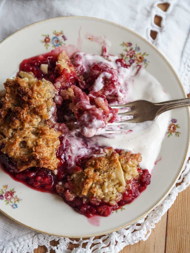 En lille tallerken med hindbær crumble og creme fraiche