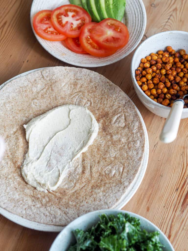 tortilla der er smurt med hummus og har fyld rundt om i skåle