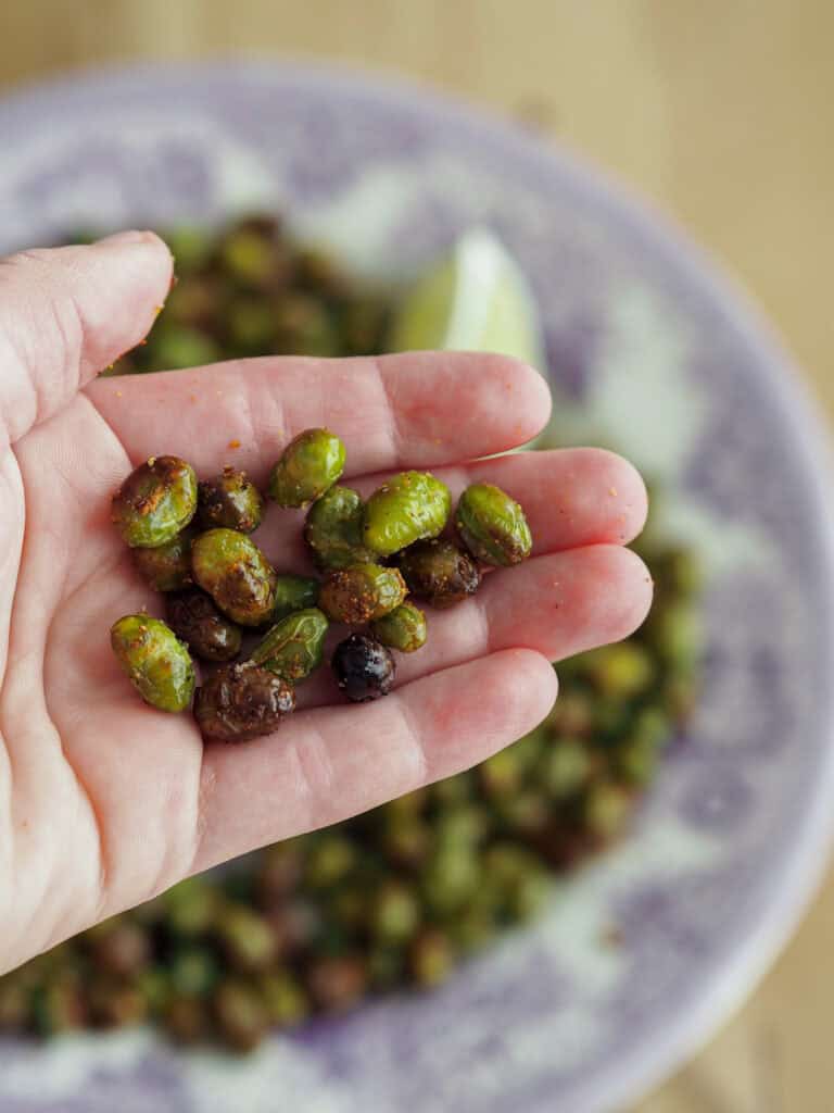 En hånd der holder nogle ovnbagte edamamebønner
