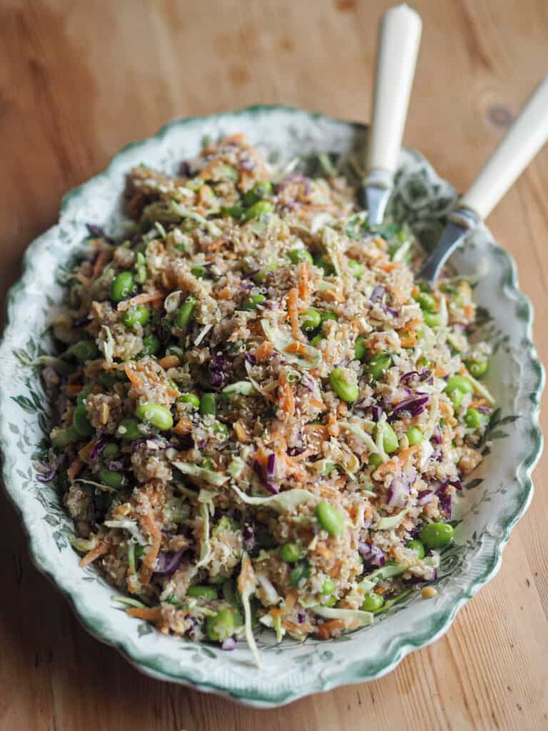 quinoasalat med mange grøntsager og peanutbutter dressing i et stort fad