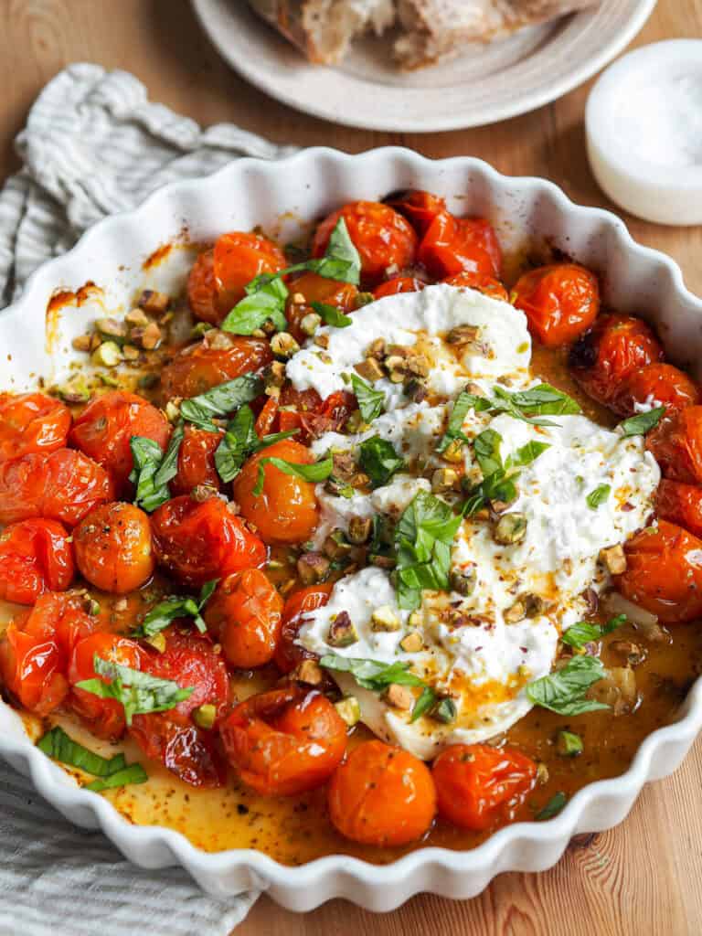 ovnbagte bagte tomater med burrata og basilikum i en ovnfast fad.